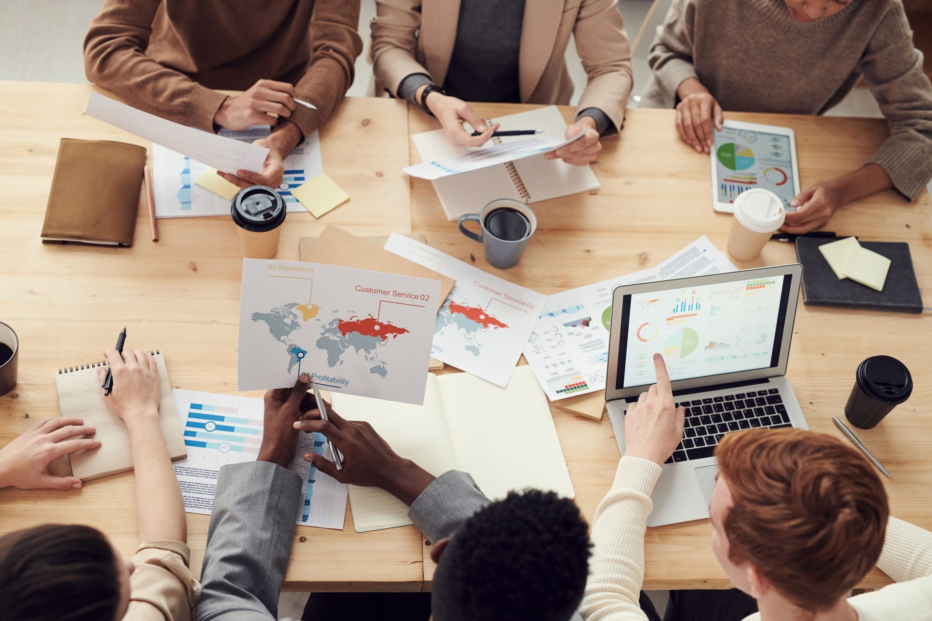 Une équipe diversifiée participant à une réunion collaborative avec des graphiques et des ordinateurs portables.