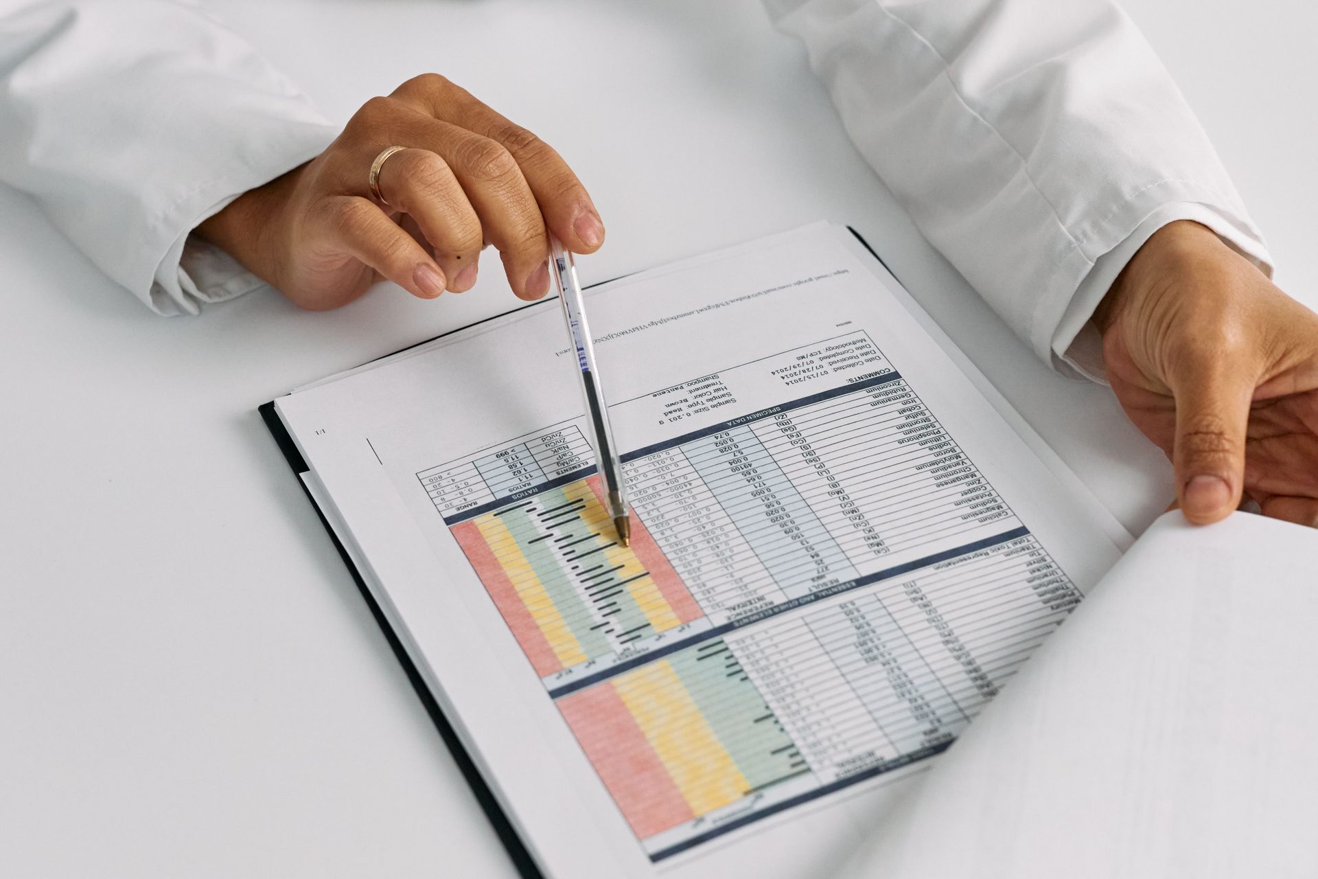 Gros plan sur des mains de médecin examinant et pointant du doigt des dossiers médicaux.