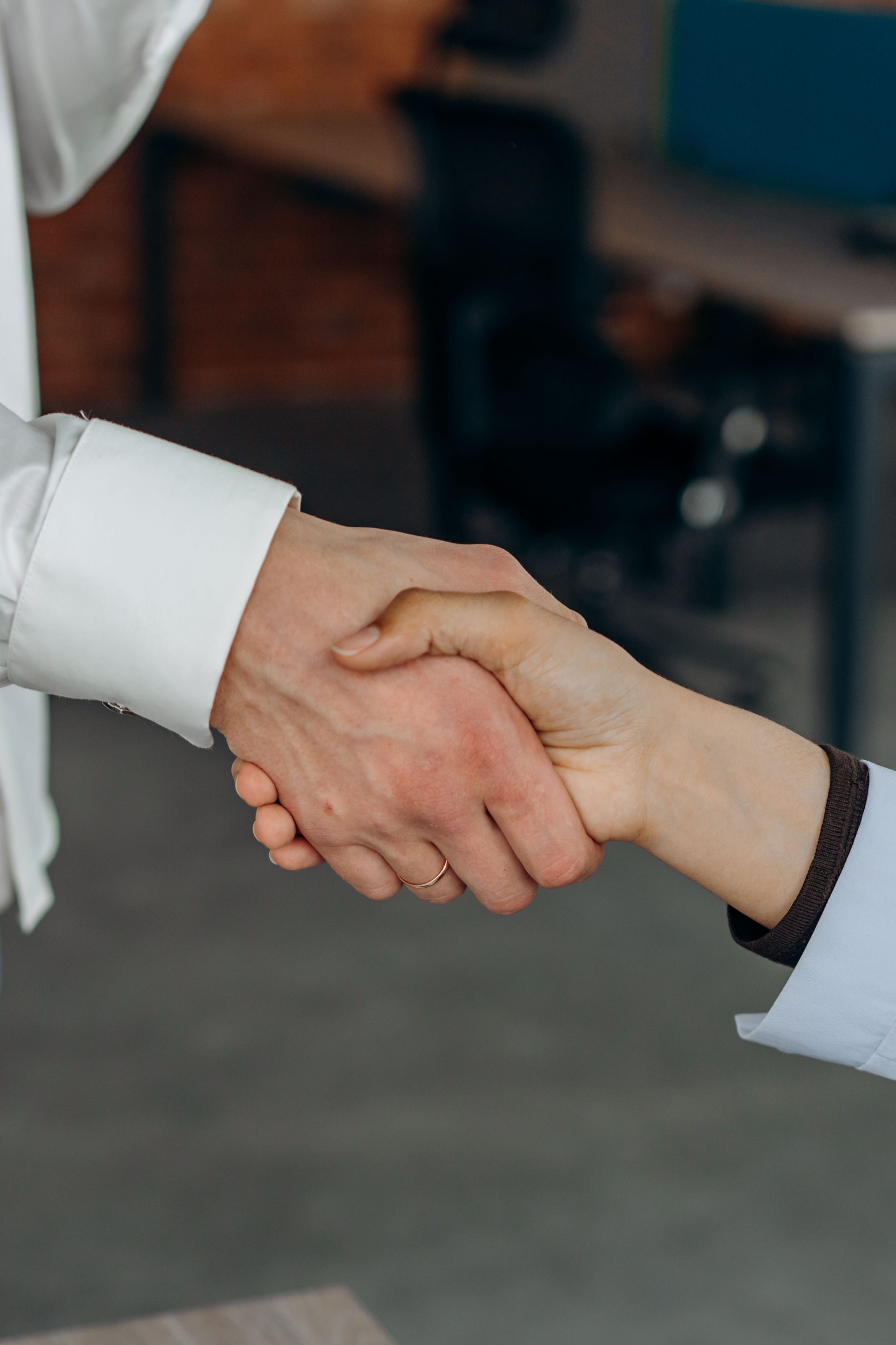 Gros plan sur une poignée de main entre deux personnes, symbolisant un partenariat ou un accord dans un cadre de bureau.